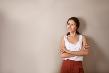 Inspiration, joy and positiveness concept. Isolated image of confident happy young woman with folded arms looking up and smiling broadly posing in new empty apartment, thinking about future interior