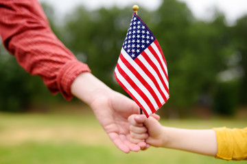 Young woman and little child holding american flag. Independence Day concept.