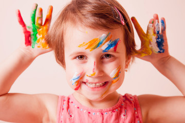 Little cute girl with children's colorful makeup showing painted hands. Happiness concept.