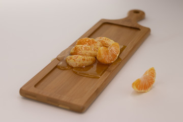 Beautifully sliced mandarin poured honey lies on a wooden board on a white background