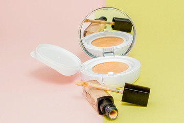 Make up products spilling on to a bright yellow and pink background with copy space