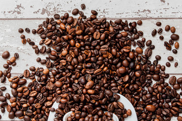 Black coffee in white cup and coffee beans on light wooden background. Top view, space for text