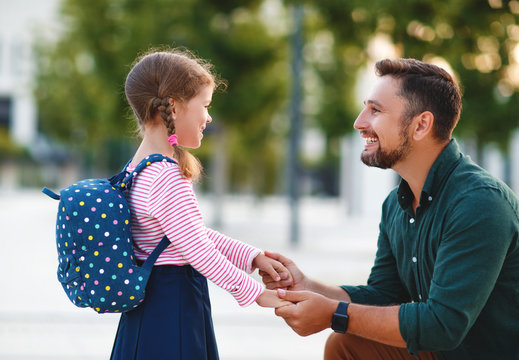 first day at school. father leads  little child school girl in first grade.