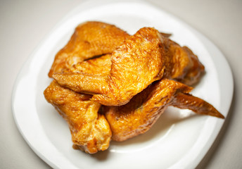 Сhicken wings on a white plate. Blurred background.