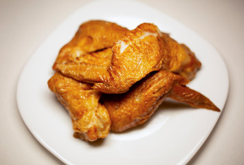 Сhicken wings on a white plate. Blurred background.