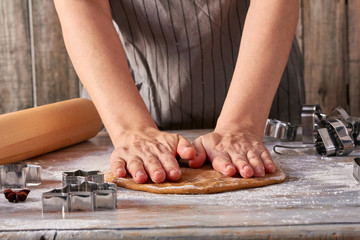 Fototapeta na wymiar Woman hands rolls up gingerbread dough on table
