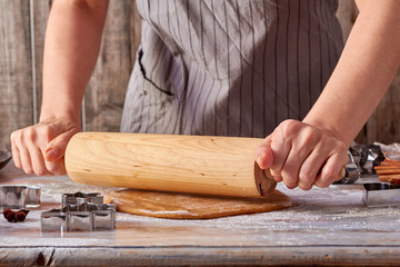 Woman hands rolling up gingerbread dough on table