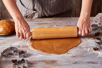 Woman hands rolling up gingerbread dough on table