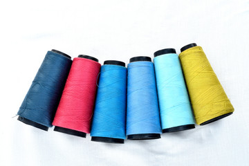 Colorful sewing thread reels on white background.