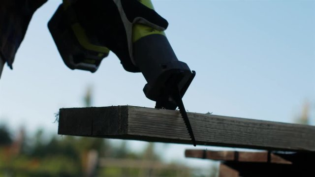 a man is sawing with an electric saber saw board in the yard