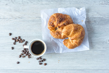 Close Up of Fresh Baked Croissant on wood table with Coffee Mug and  news paper on Relaxing Morning at Home, Bread and coffee, breakfast Healthy food of the city life