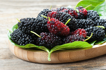 Fresh ripe black mulberry berry fruit with leaf on rustic wooden background, blackberry summer red...