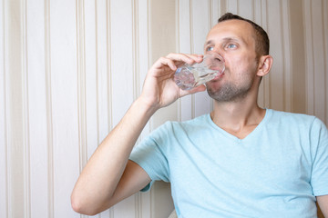 Fototapeta na wymiar the guy is drinking clean glass water
