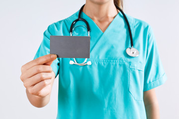 Woman medical doctor hand holding a blank card on gray background.