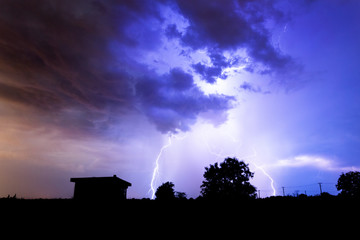 Naklejka na ściany i meble Lightning flashes over the night sky during thunderstorm.