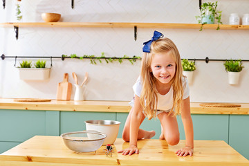 Baking with children: little happy kid, adorable toddler girl helping mother to prepare delicious muffins in the kitchen