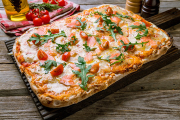 Pizza with salmon on Roman dough with tomatoes and aragula