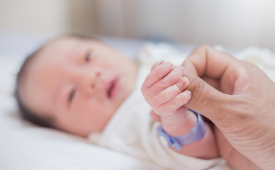 Asian parent hands holding newborn baby fingers, Closeup mother’s hand holding their new born baby. Together love family nursery healthcare and medical father’s day concept