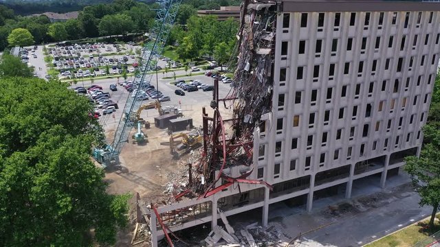 Aerial video of old office building being demolished by a wrecking ball taking apart the steel beams and concrete walls in Maryland United States