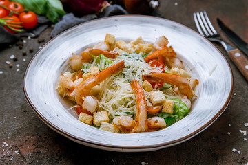 salad caesar with shrimps on dark concrete rustic background