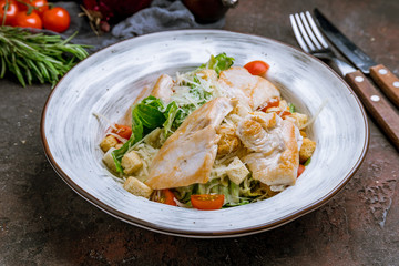 Salad caesar with chicken on dark concrete rustic background