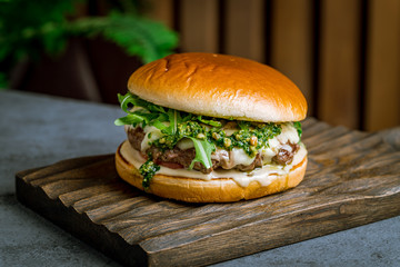 Burger with meat and aragula and sause pesto on the board