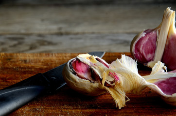 Destroyed head of garlic on the kitchen cutting board on a wooden old table.