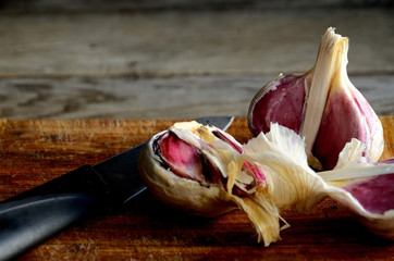 Destroyed head of garlic on the kitchen cutting board on a wooden old table.