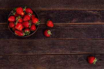 strawberries on a wooden background in a clay cup