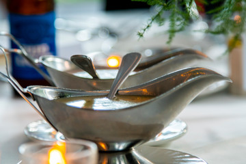 detailed shot of luxury silver gravy bowls containing salad dressing at a banquet for a wedding...