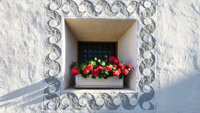 typical window with sgraffito and red flowers in Engadin