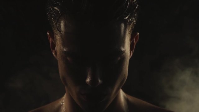 Sexy sport stripped guy in water drops with smoke on isolated black background