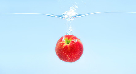 Red apple falling deeply under water with splash