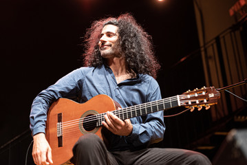 Obraz na płótnie Canvas handsome man with long hair playing classical guitar