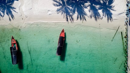 A long tail boat anchor to Koh Touch Beach on Koh Rong with palm tree shadows, Cambodia