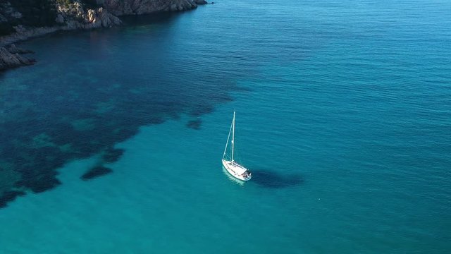 View from above, stunning aerial view of a sailing boat floating on a beautiful turquoise clear sea. Maddalena Archipelago National Park, Sardinia, Italy