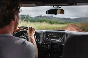 Man driver driving off road trail path with 4x4 car on adventure trip travel holiday. Hawaii drive in the rain bad weather.