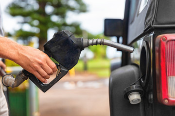 Gas station pump. Man filling gasoline fuel in car holding nozzle. Close up.