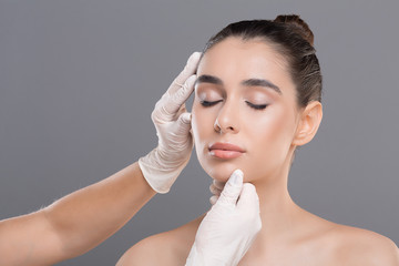 Young woman on consultation at beautician, grey background