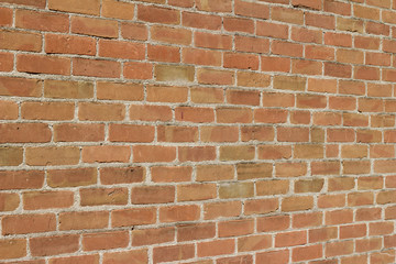 Antique weathered brick wall background in varying shades of reddish brown (angle view)