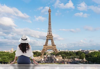 Deurstickers Jonge reizigersvrouw in witte hoed die de toren van Eiffel, beroemd oriëntatiepunt en reisbestemming in Parijs bekijkt © SasinParaksa