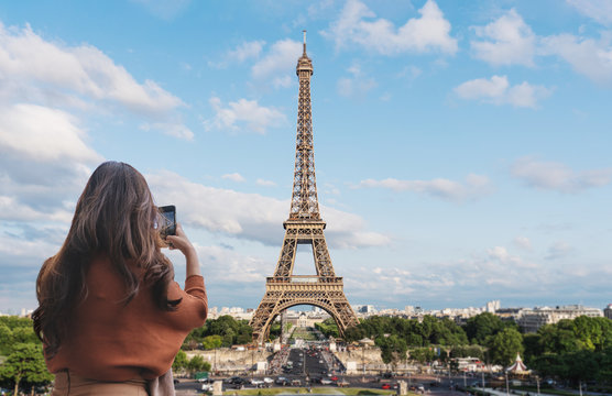 Traveler woman taking photo of Eiffel Tower, famous landmark and travel destination in Paris, France by mobile smartphone