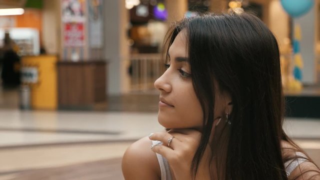 Young beautiful caucasian girl with brunette hair sitting in the mall