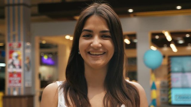 Young cheerful caucasian girl with brunette hair smiling in the mall