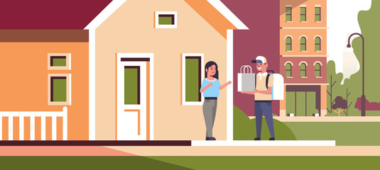 woman receiving order from man courier in cap with backpack and paper package express food delivery from shop or restaurant concept modern house building exterior flat horizontal full length