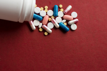 Piles of pills and capsule on red background. Copy space for text