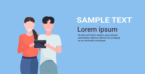 couple holding ultrasound scan of their baby future parents standing together happy family parenthood concept flat portrait horizontal