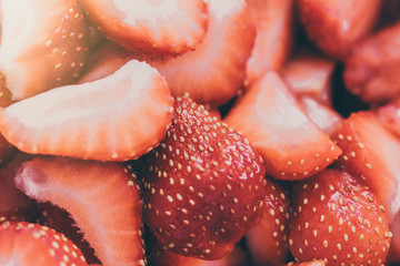 Strawberry close-up sliced. Bright red background. Sunlight.