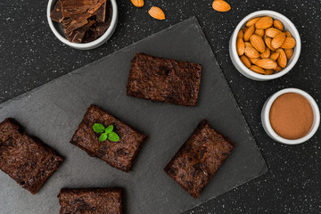 Fototapeta na wymiar Dark chocolate and cocoa brownie fudge cakes dessert with mint against black and grey stone background