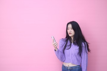 happy excited  glad to receive text message informing about salary, rejoices good news, stares at mobile phone, actively from happiness, Beautiful Asian models over  pink  background for advertising c